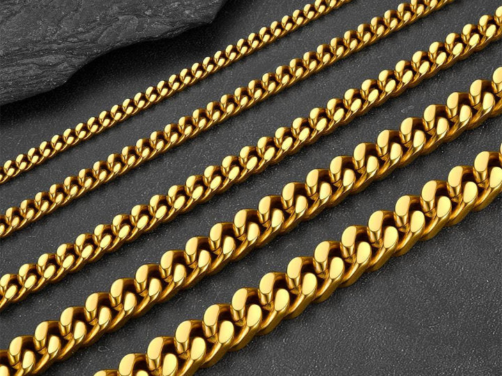 A close-up of gold Cuban link chains in various sizes, from thin to thick, on a dark textured surface