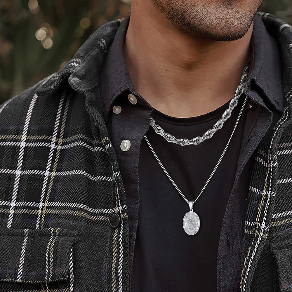 Man wearing a black plaid jacket and black shirt with silver necklaces.