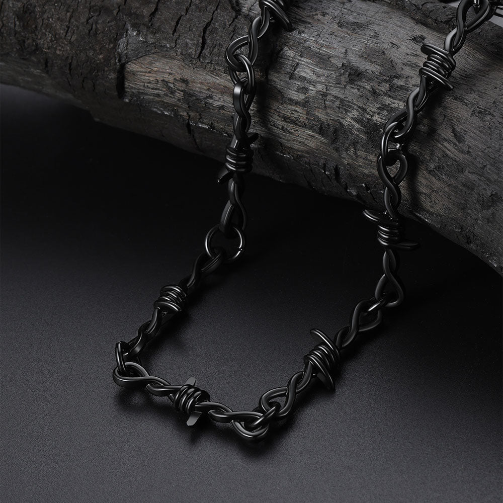 Black chain necklace on a dark surface with a wooden background