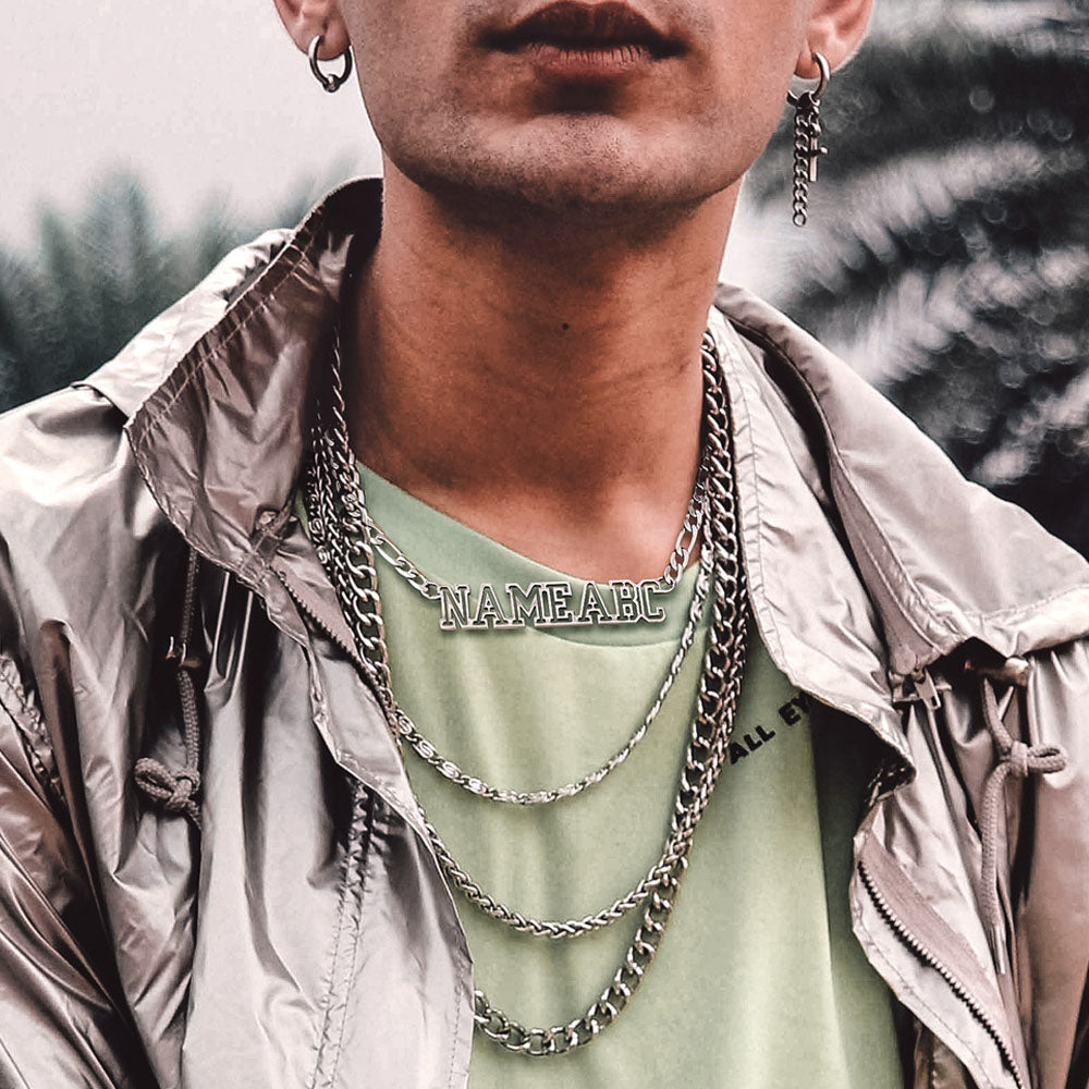 Person wearing multiple chain necklaces with a blurred natural background