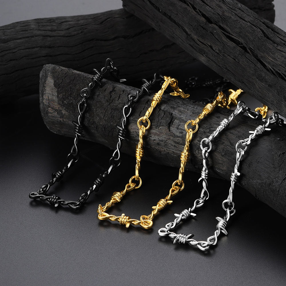 Three chain necklaces in black, gold, and silver on a dark surface.