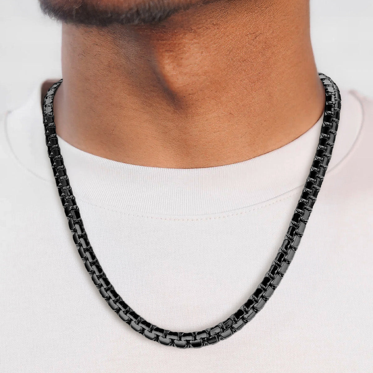 Black chain necklace worn by a person on a white background