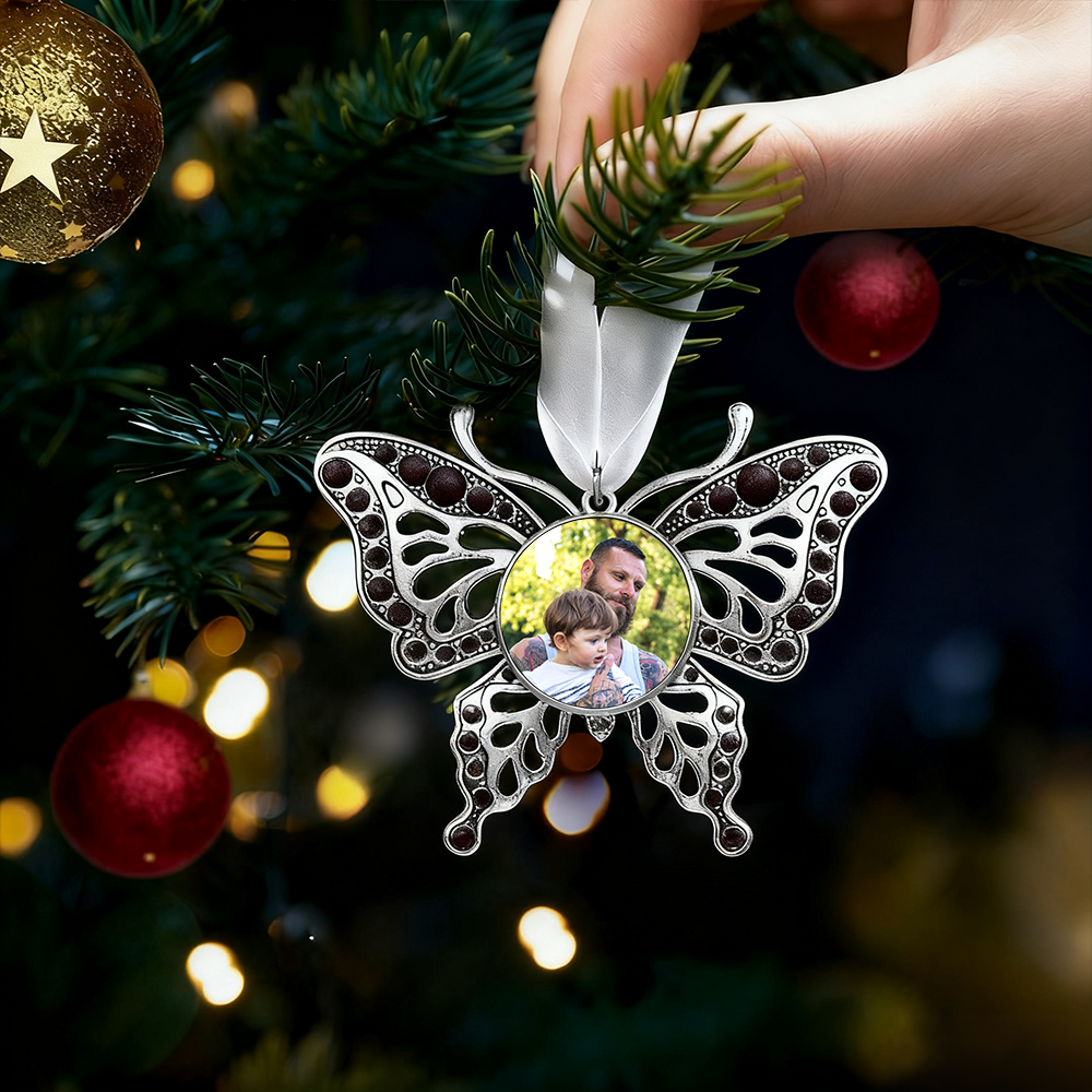 Butterfly-shaped ornament with a photo of a man and child on a Christmas tree.