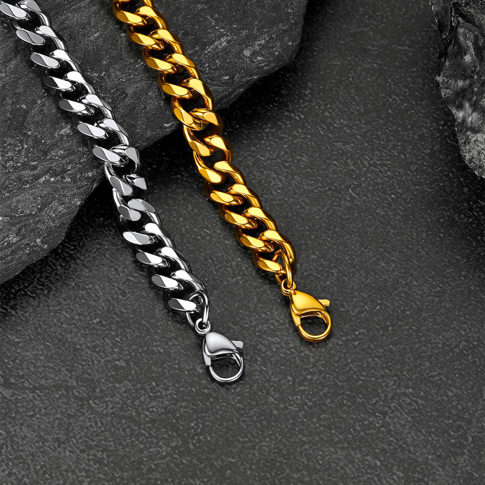 Two chain bracelets, one silver and one gold, on a dark stone surface.