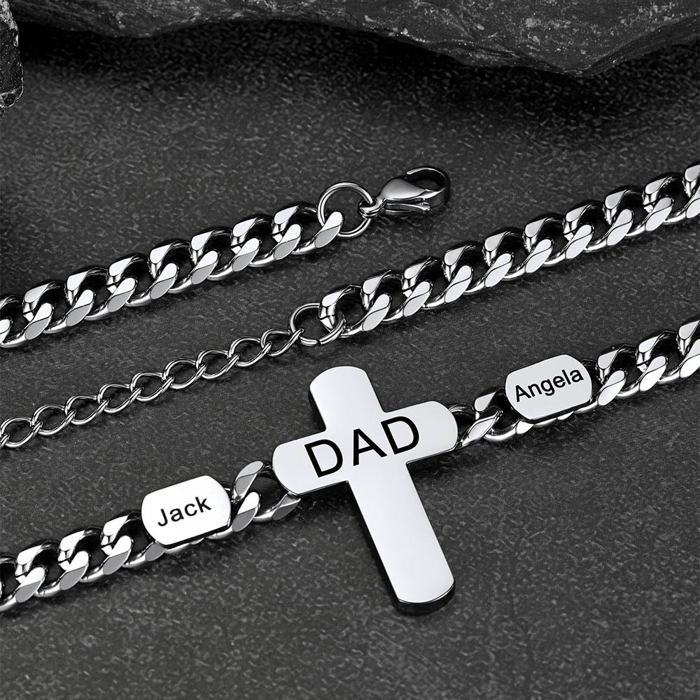 Silver chain bracelet with cross pendant and engraved names on a dark surface