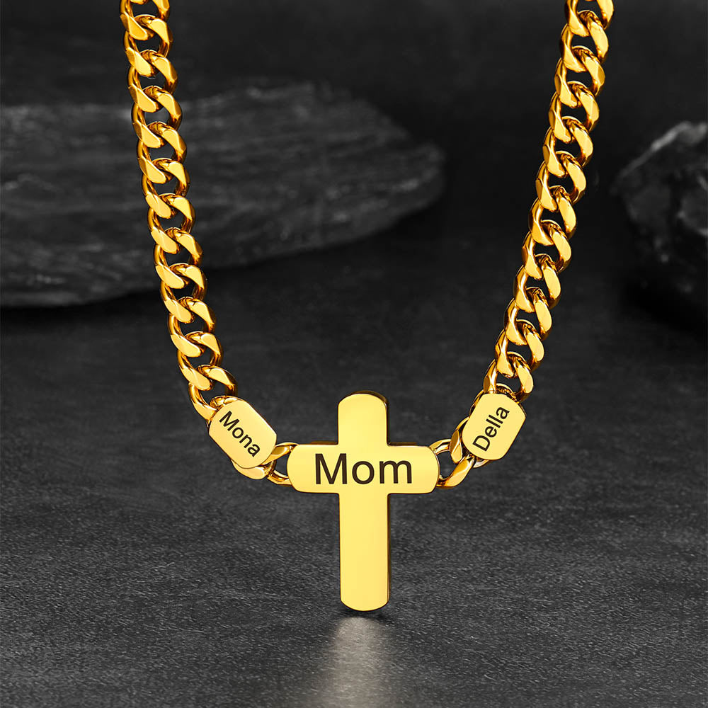 Gold necklace with a cross pendant and engraved names on a dark background