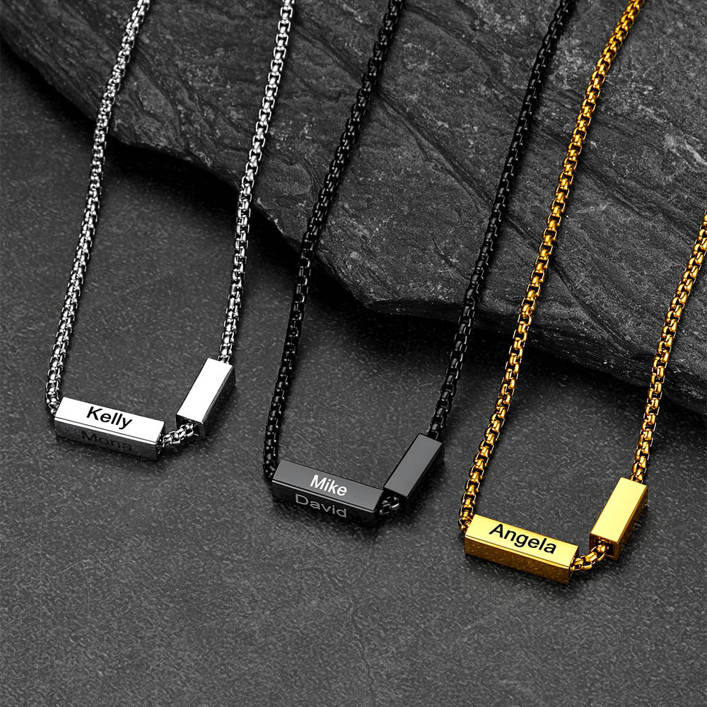 Three personalized necklaces with name tags on a dark stone surface