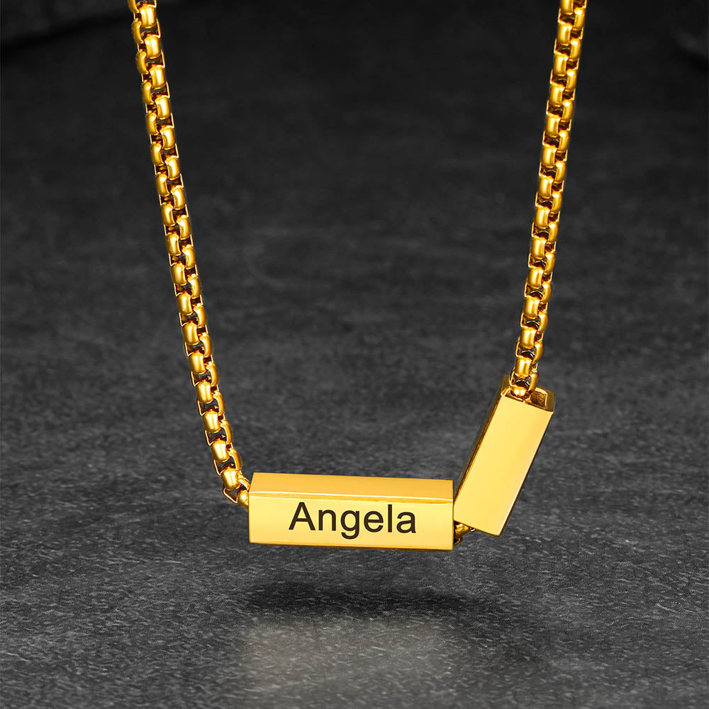 Gold necklace with a rectangular pendant engraved with 'Angela' on a dark background