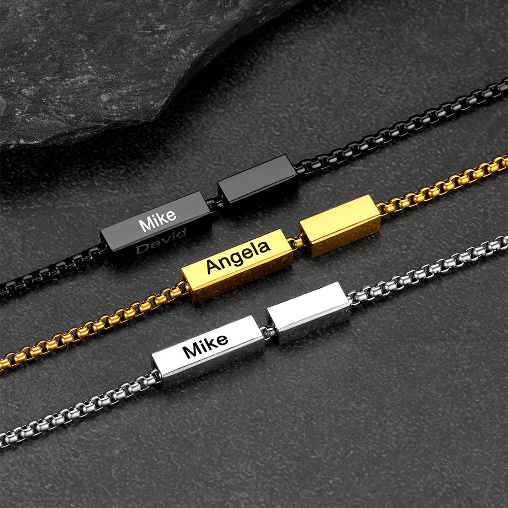 Three name bracelets in black, gold, and silver on a dark surface
