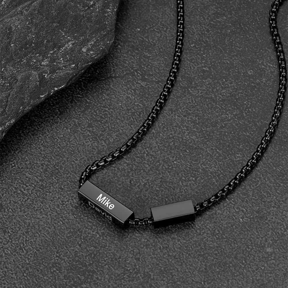 Black chain necklace with nameplate on a dark stone surface