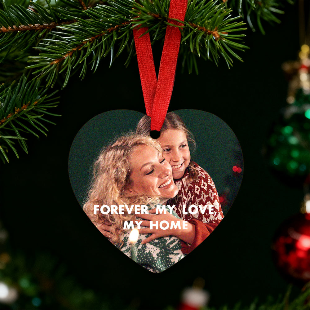 Heart-shaped photo ornament with a woman and child, surrounded by Christmas tree branches and decorations.