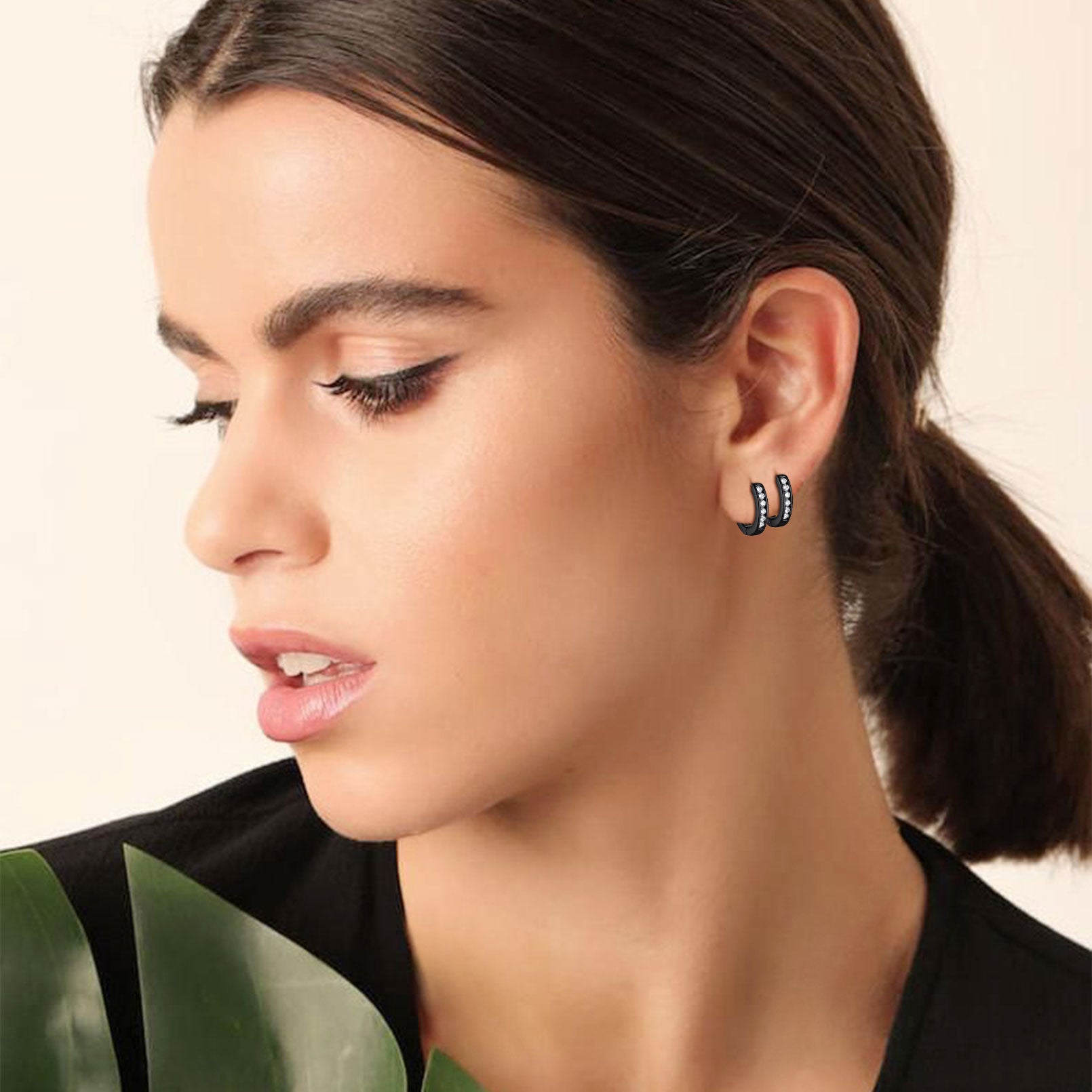 Woman wearing sterling silver black onyx huggie hoop earrings