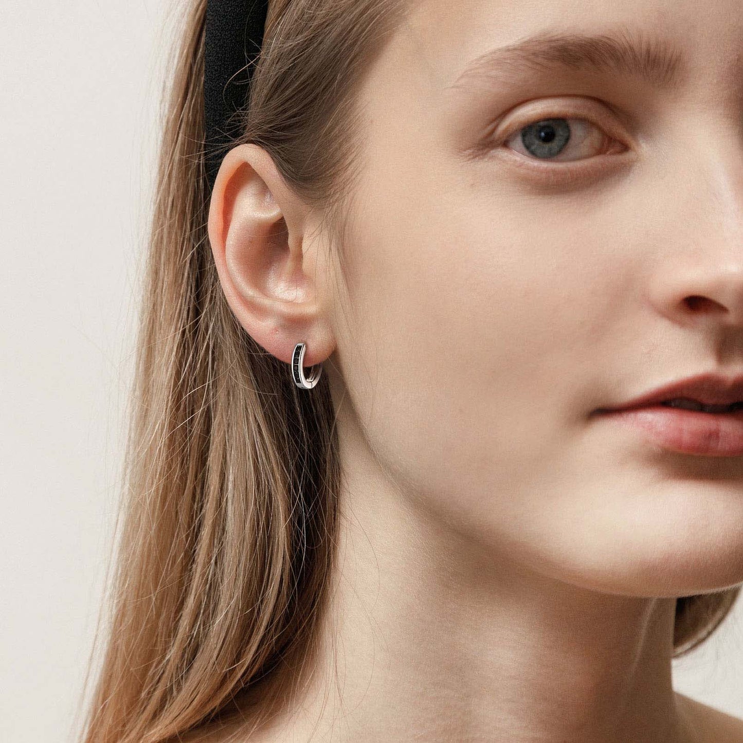 Woman wearing silver black onyx huggie earrings, close-up