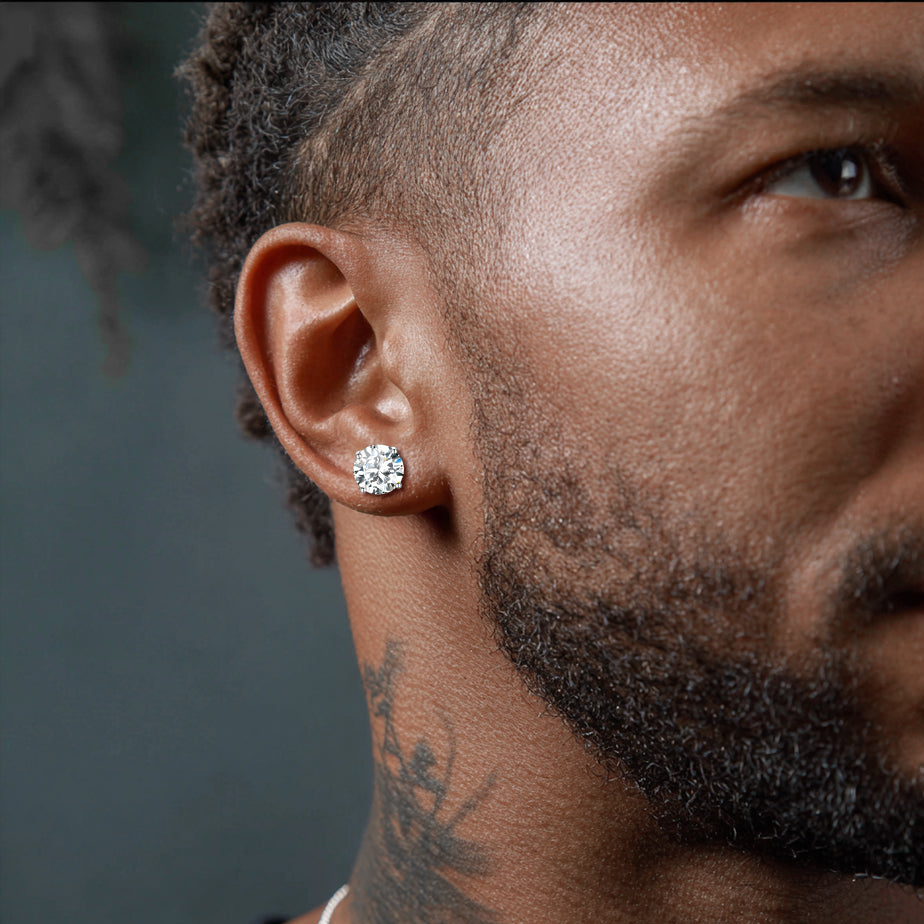 Close-up of a man wearing a diamond earring with a dark background