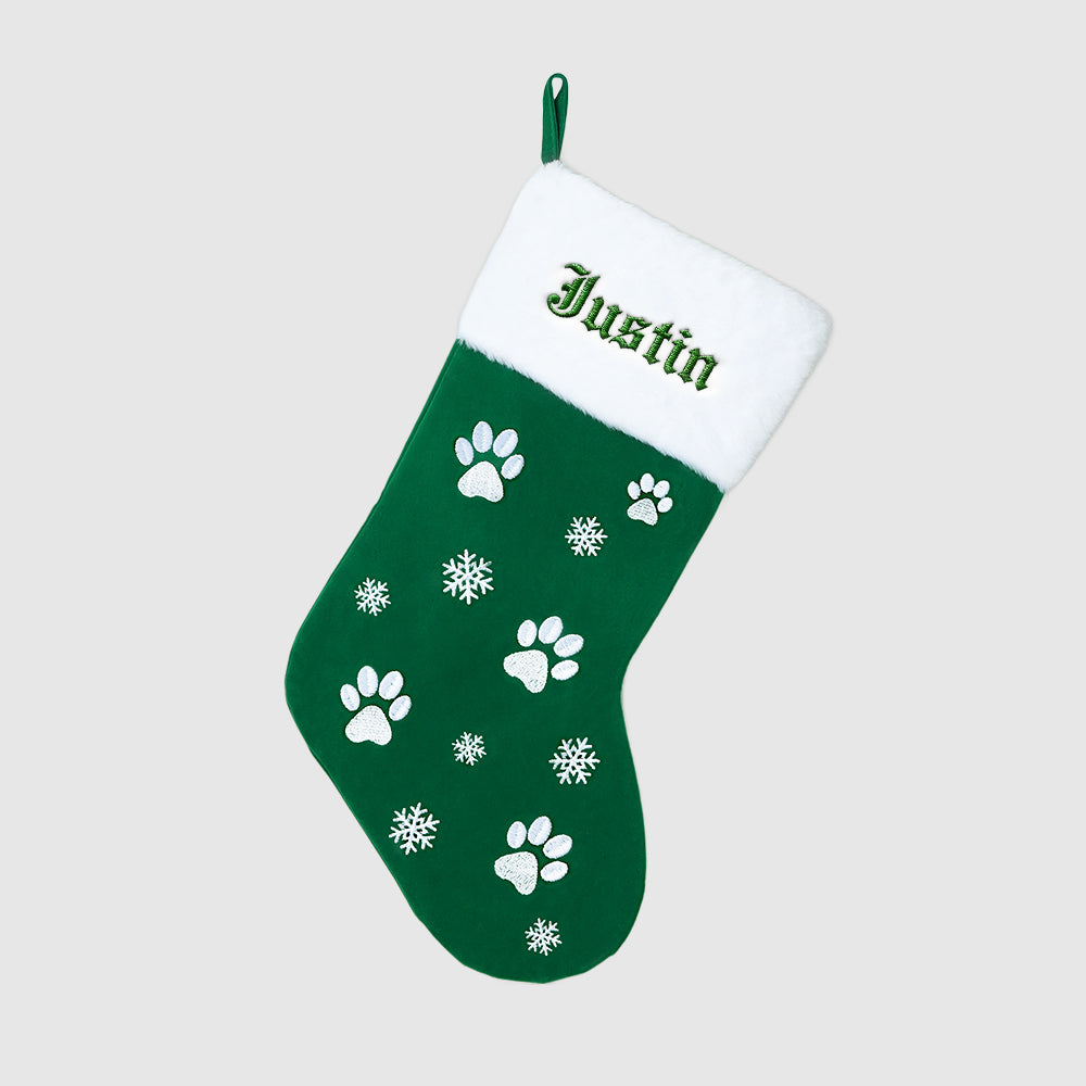 Green Christmas stocking with white paw prints and snowflakes, personalized with 'Justin'.
