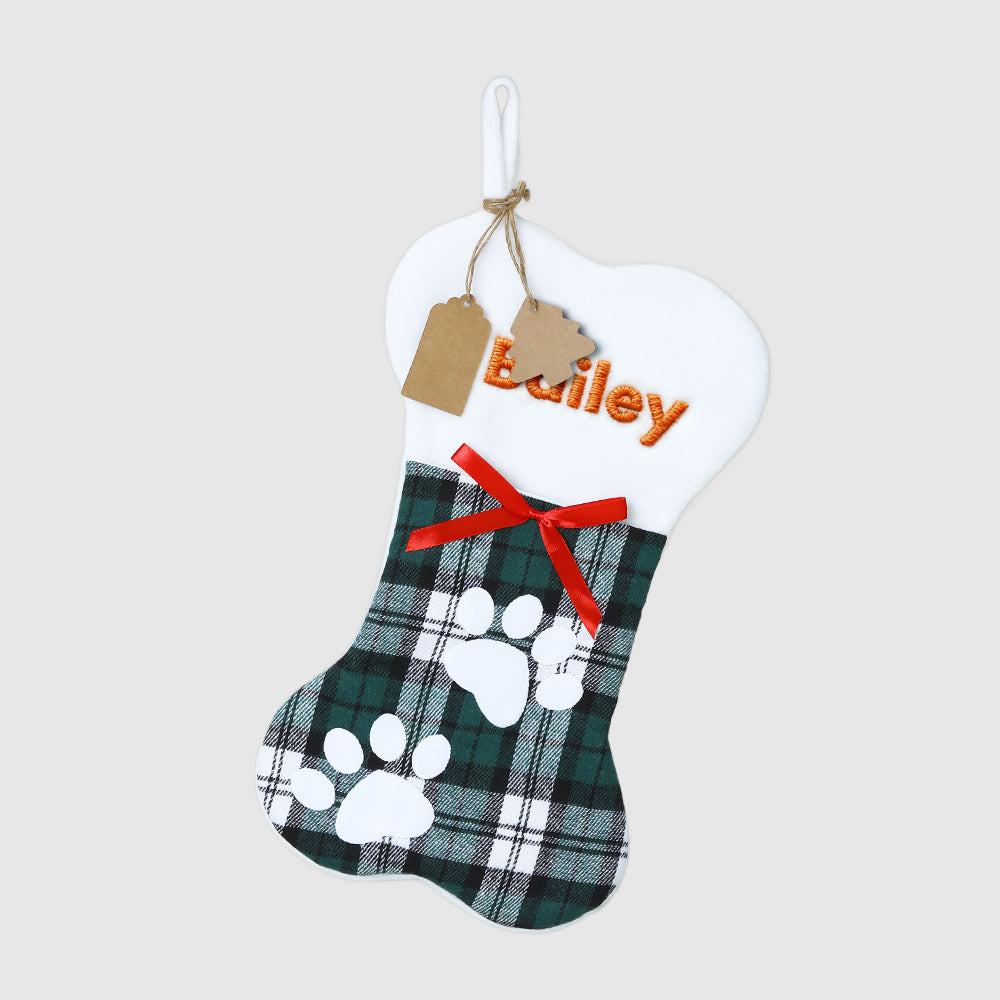 Personalized pet stocking with plaid design, paw prints, and red bow on a light gray background.