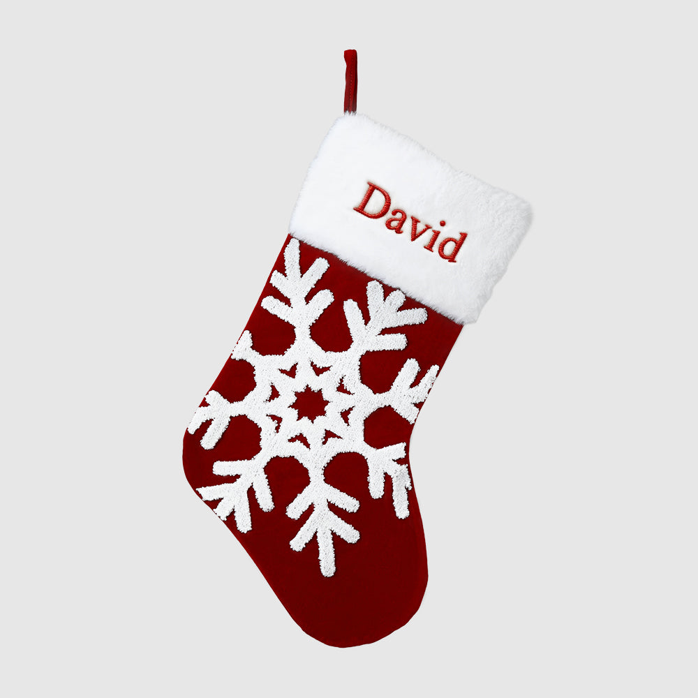 Red Christmas stocking with white snowflakes and 'David' embroidered on a light gray background