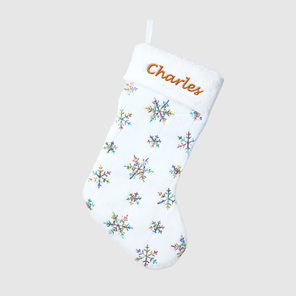White Christmas stocking with colorful snowflake patterns and embroidered name 'Charles' on a light gray background.