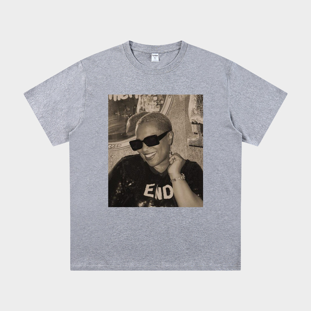 Gray t-shirt with a printed design of a person wearing sunglasses and a cap on a white background