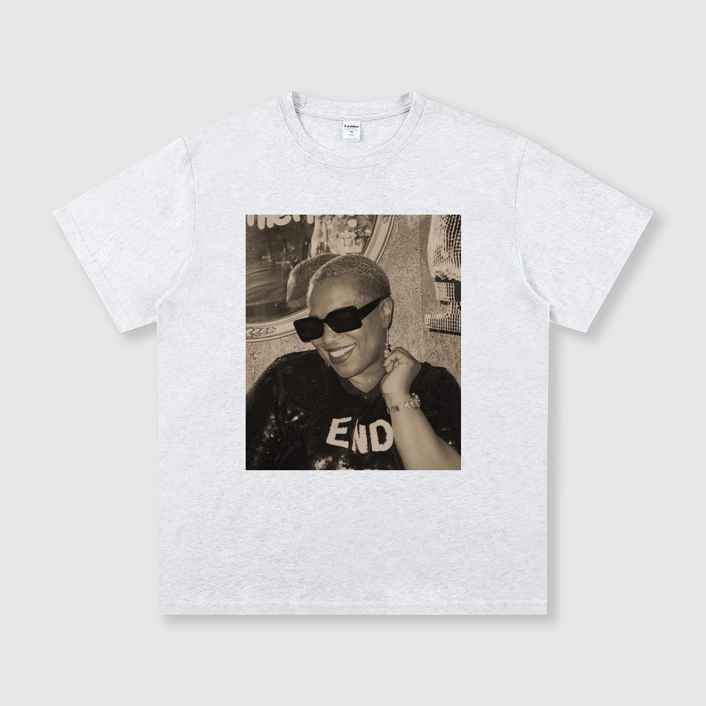 White t-shirt with a printed design of a person wearing sunglasses and a cap on a light gray background