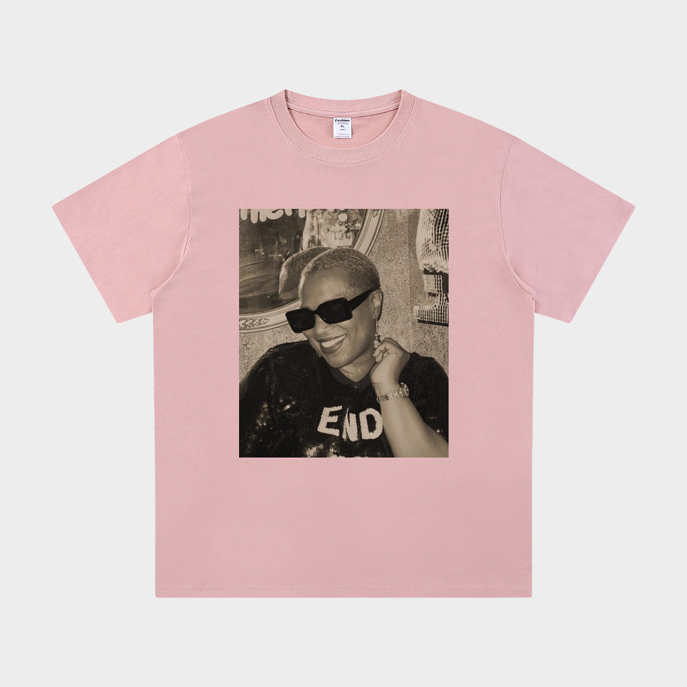 Pink t-shirt with a graphic of a person wearing sunglasses and a cap on a white background