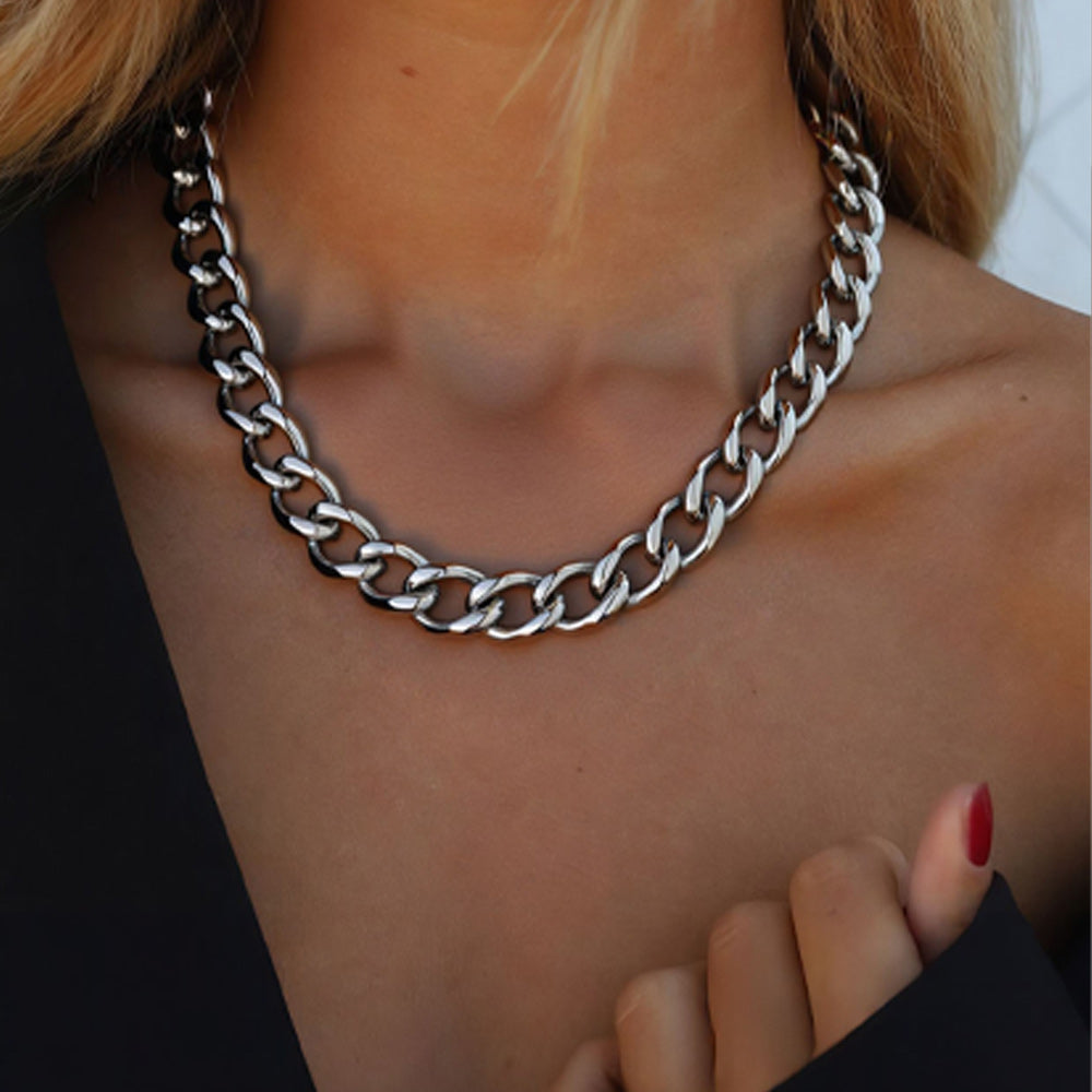 Silver chain necklace worn by a person with a blurred background