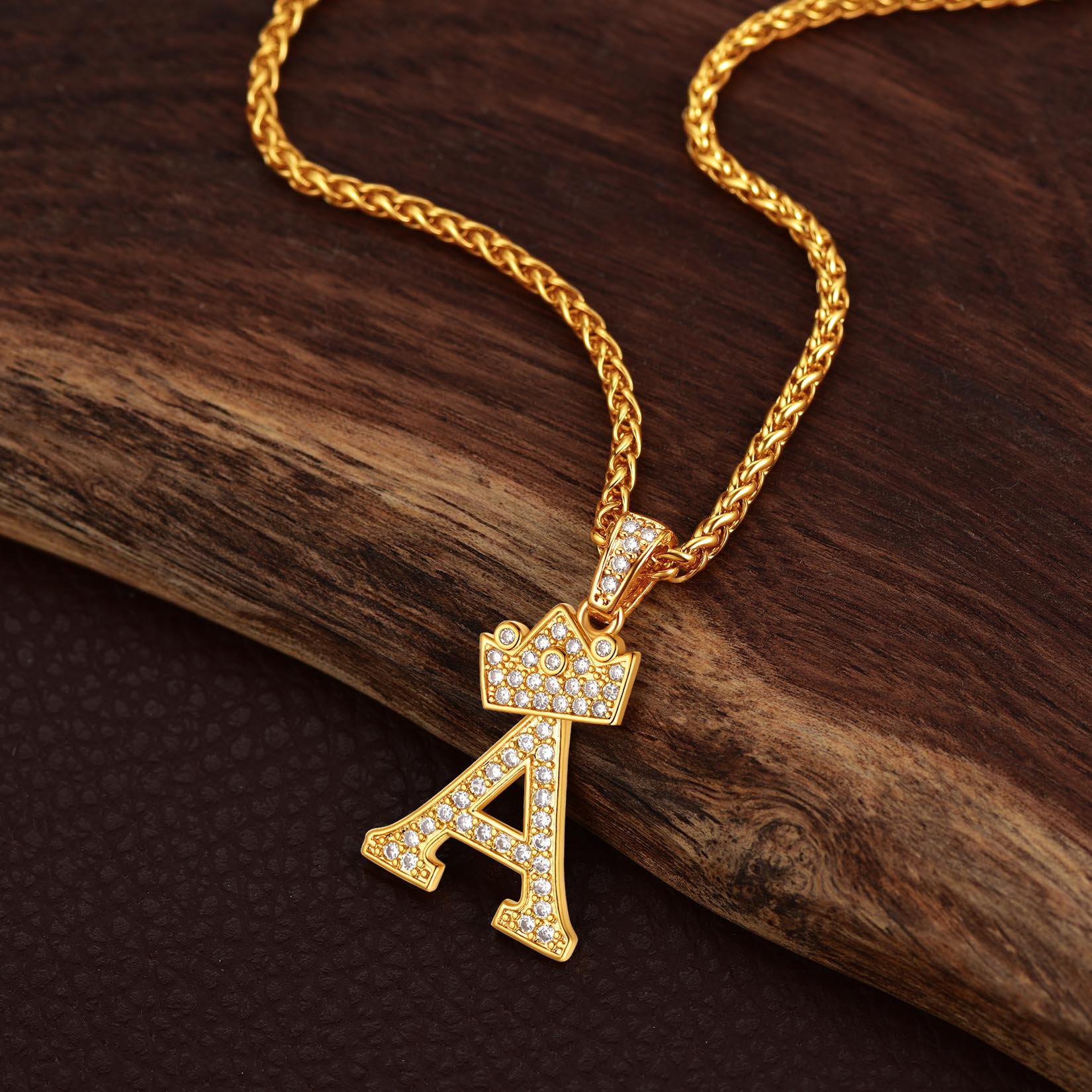 Gold necklace with a letter 'A' pendant on a wooden surface