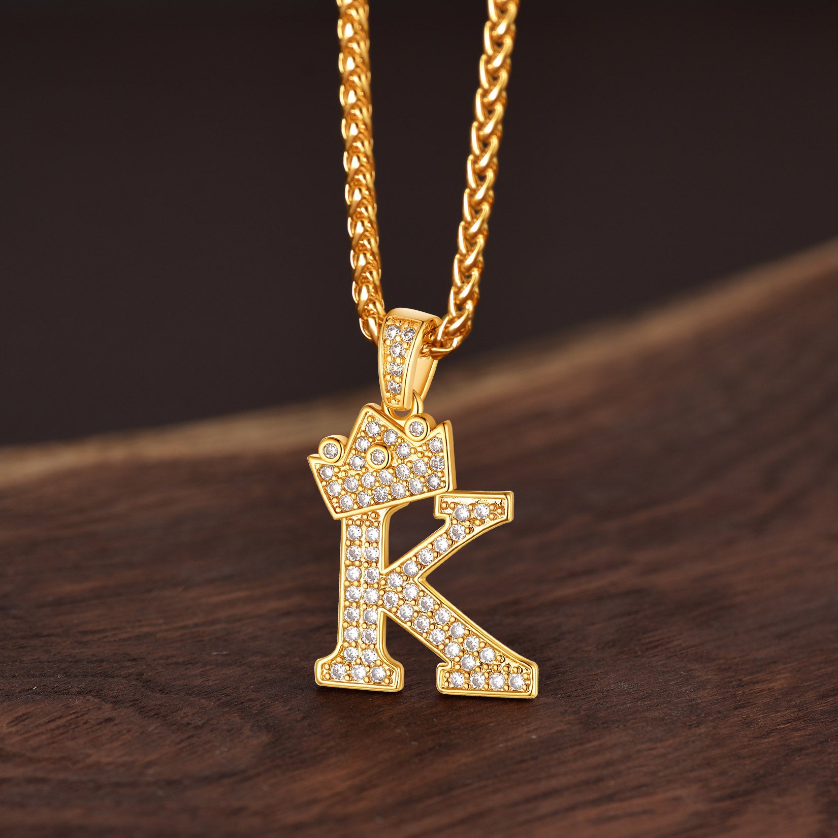 Gold necklace with a letter 'K' pendant on a wooden surface