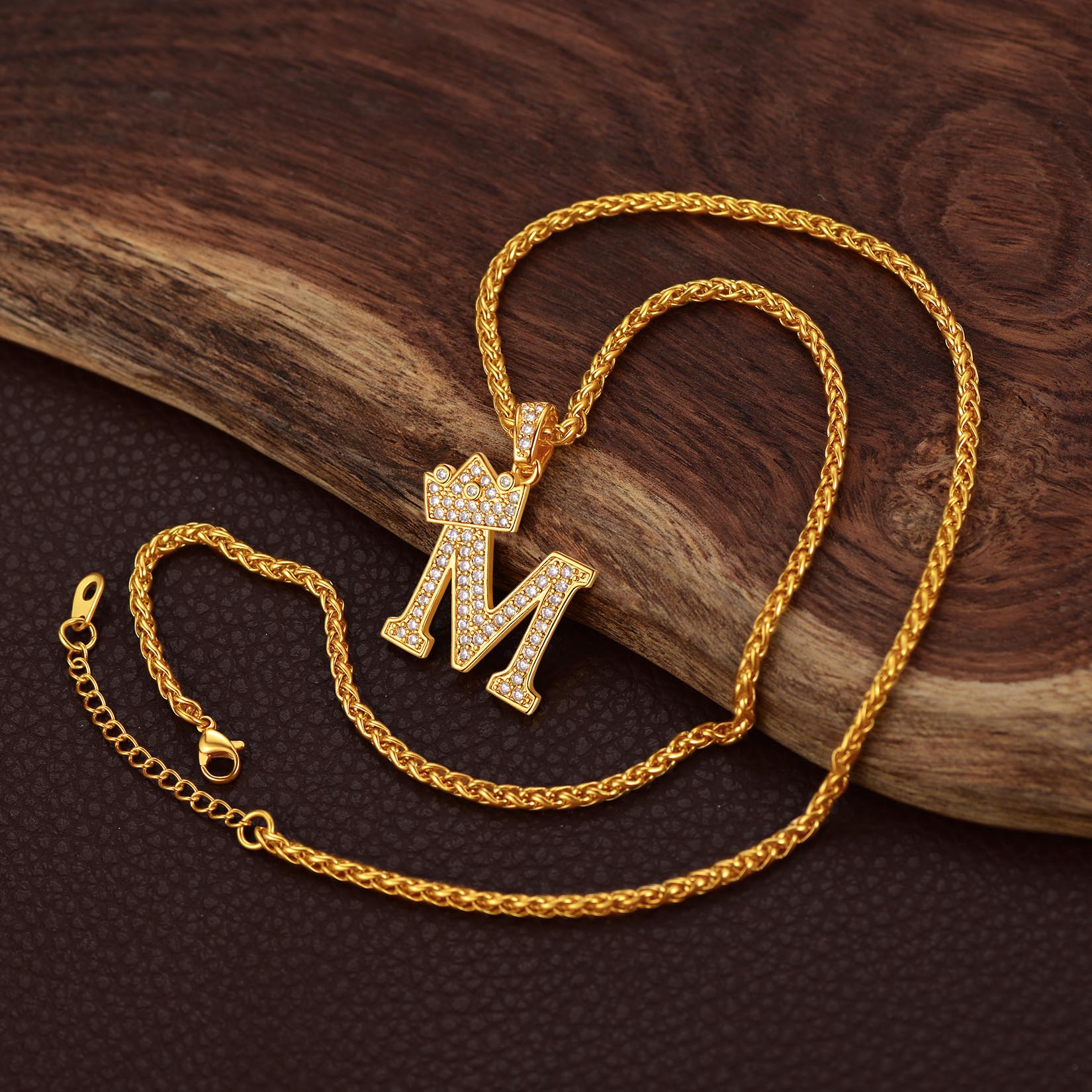 Gold necklace with a 'M' pendant on a wooden surface