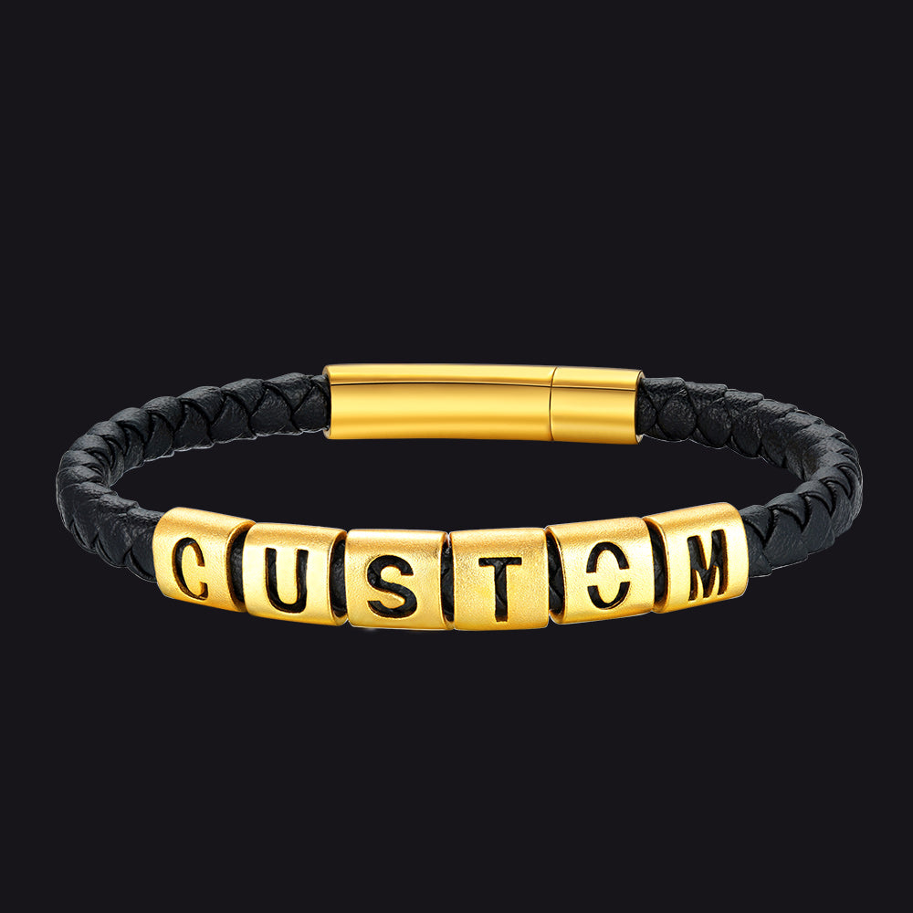 Black leather bracelet with gold cylindrical and rectangular beads on a black background