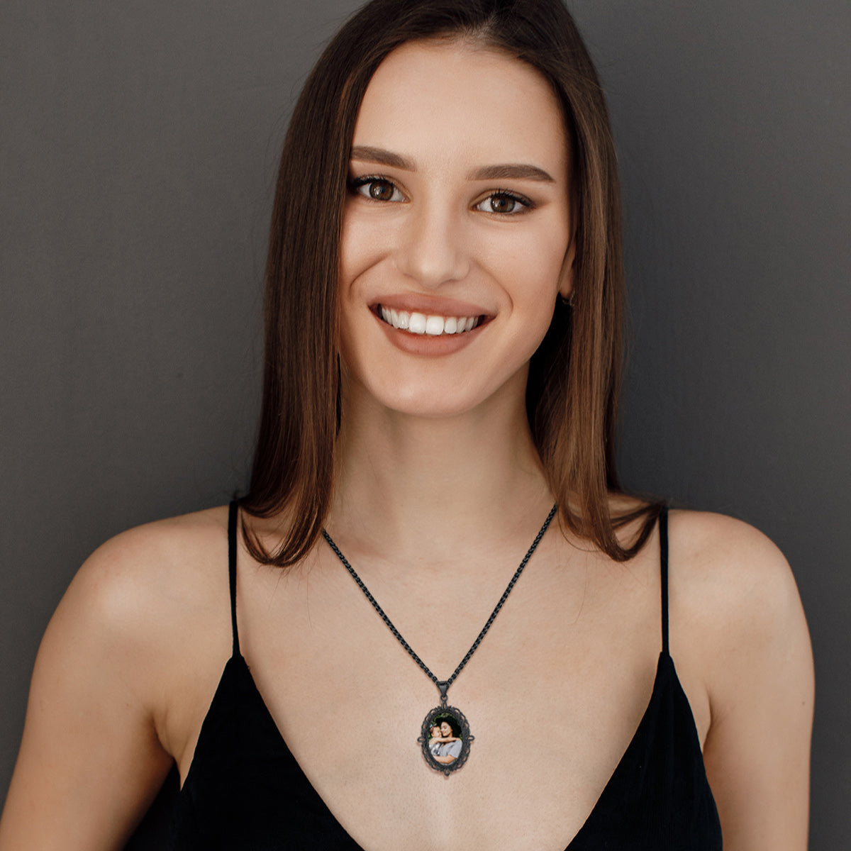 Woman wearing personalized photo necklace, smiling at the camera.