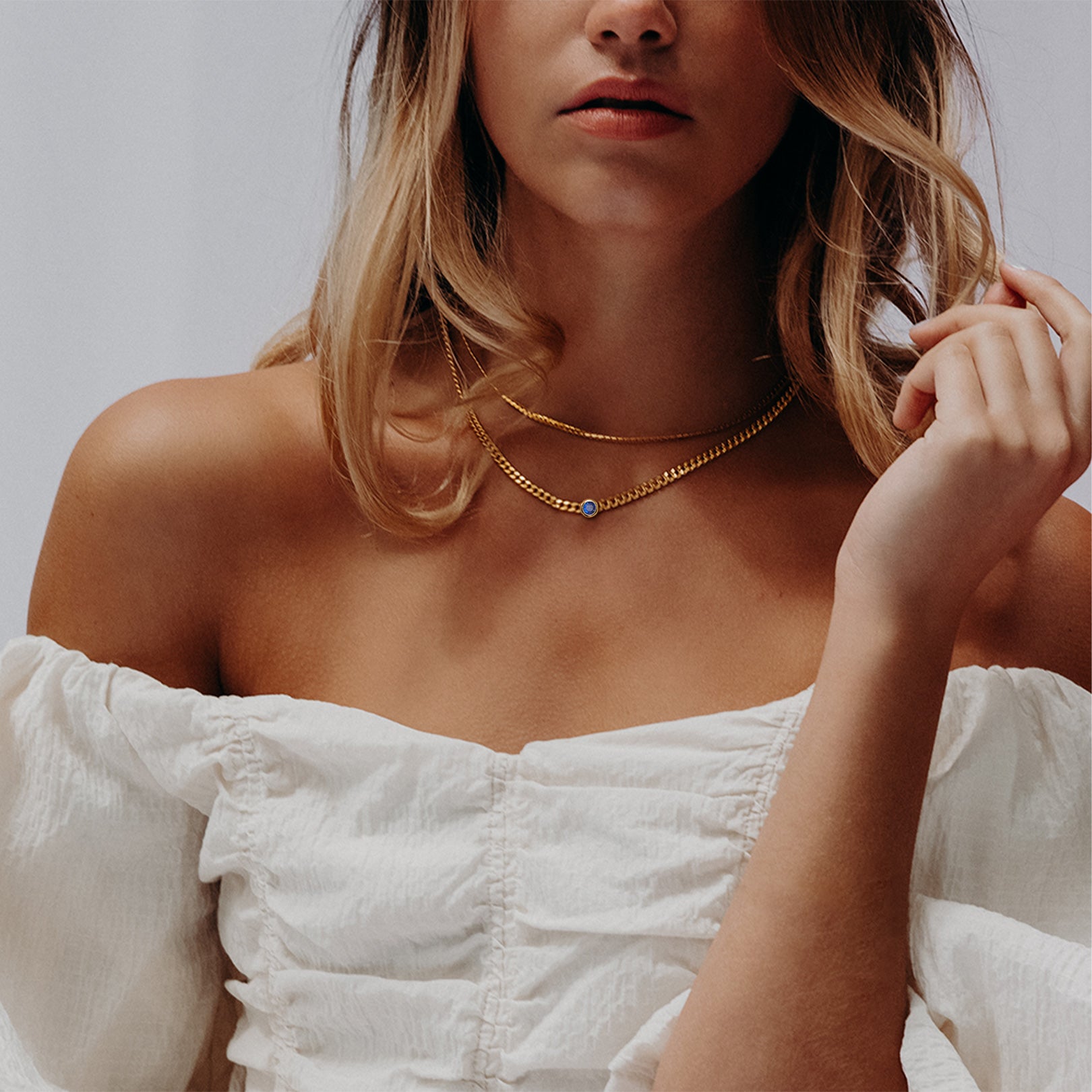Model wearing minimalist gold necklace with off-shoulder dress