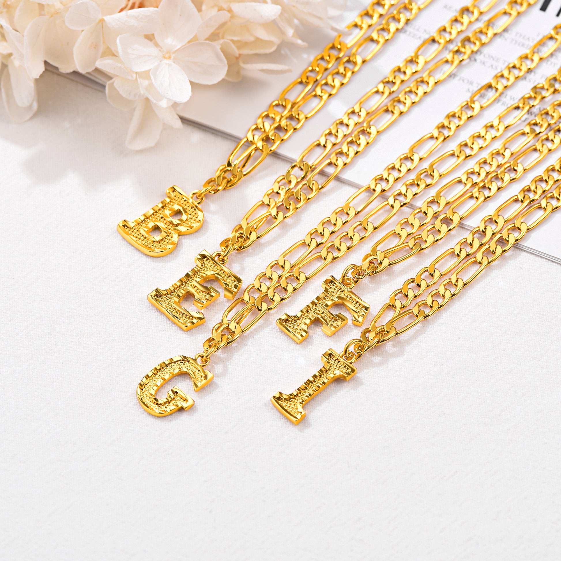 Close-up of stainless steel letter pendant on Figaro chain