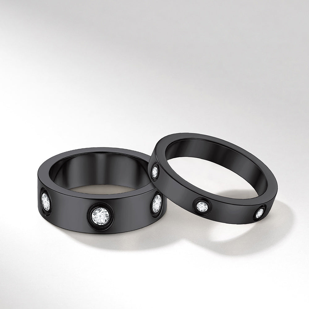 Two black couple rings with embedded diamonds on a light gray background