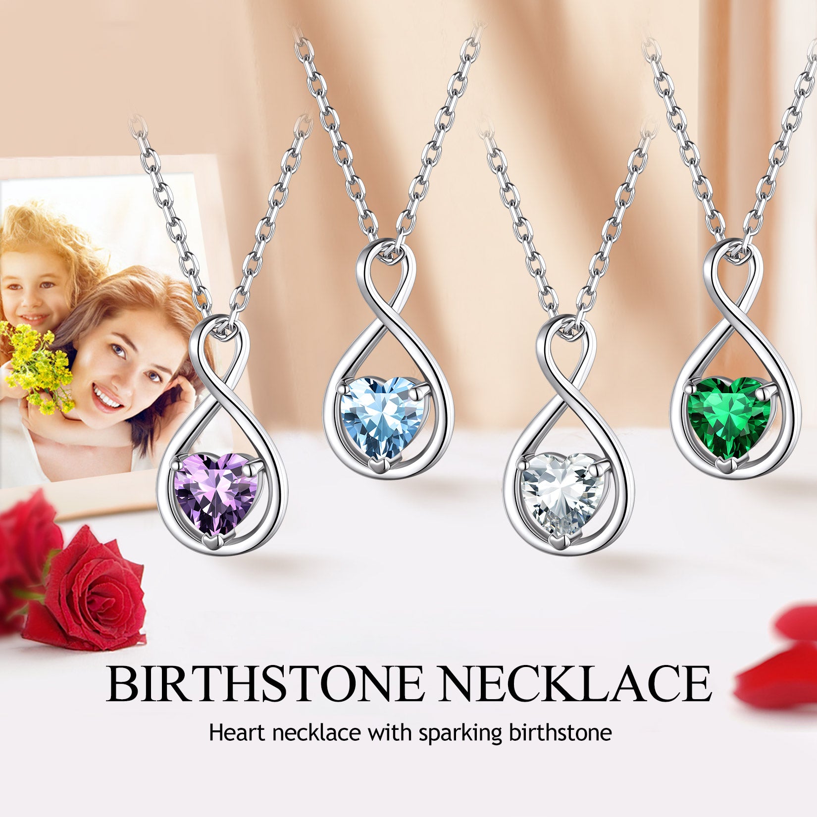 Four birthstone necklaces with heart pendants on a white surface with flowers and a photo in the background.