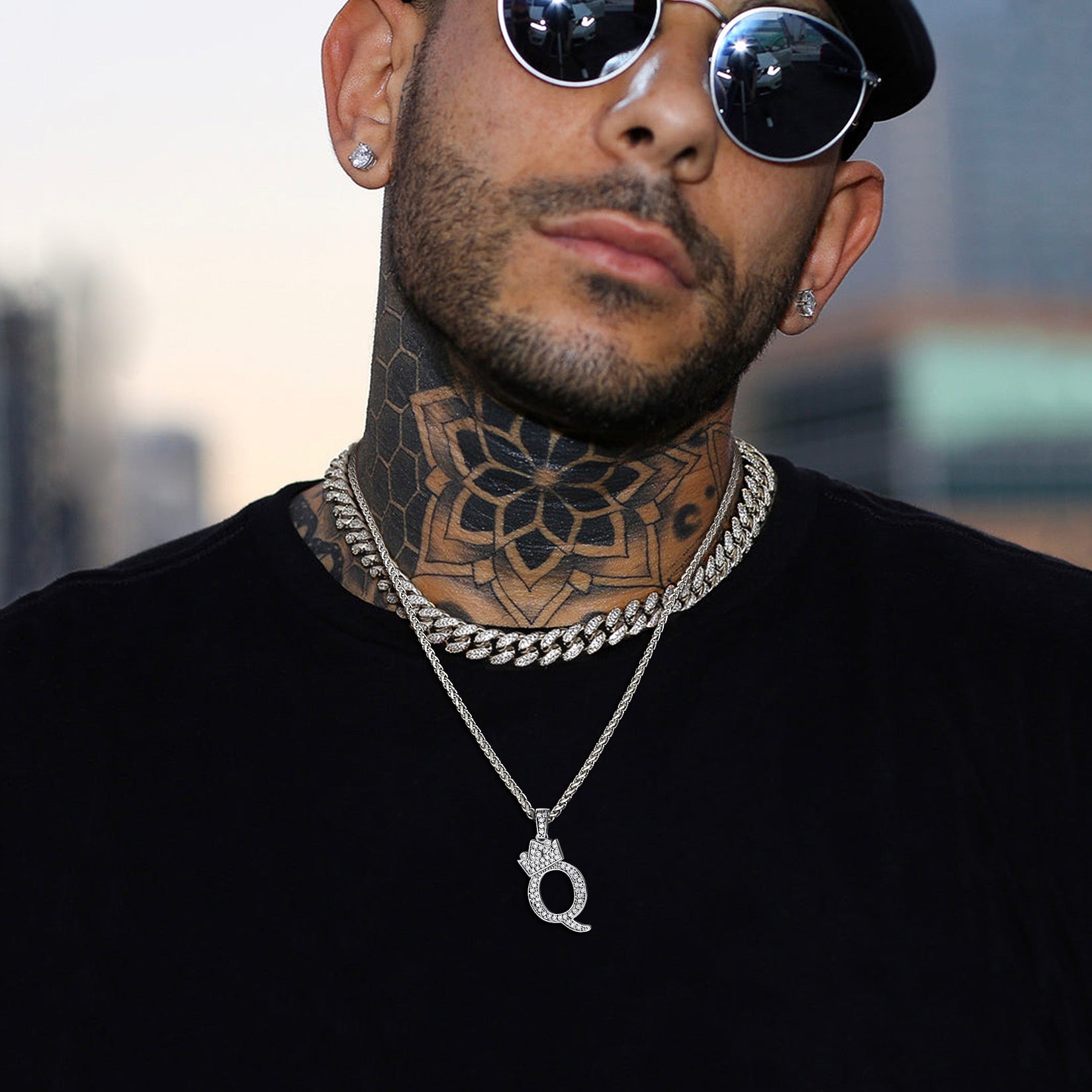 Man wearing sunglasses, black shirt, and silver Q initial chain necklace with pendant.