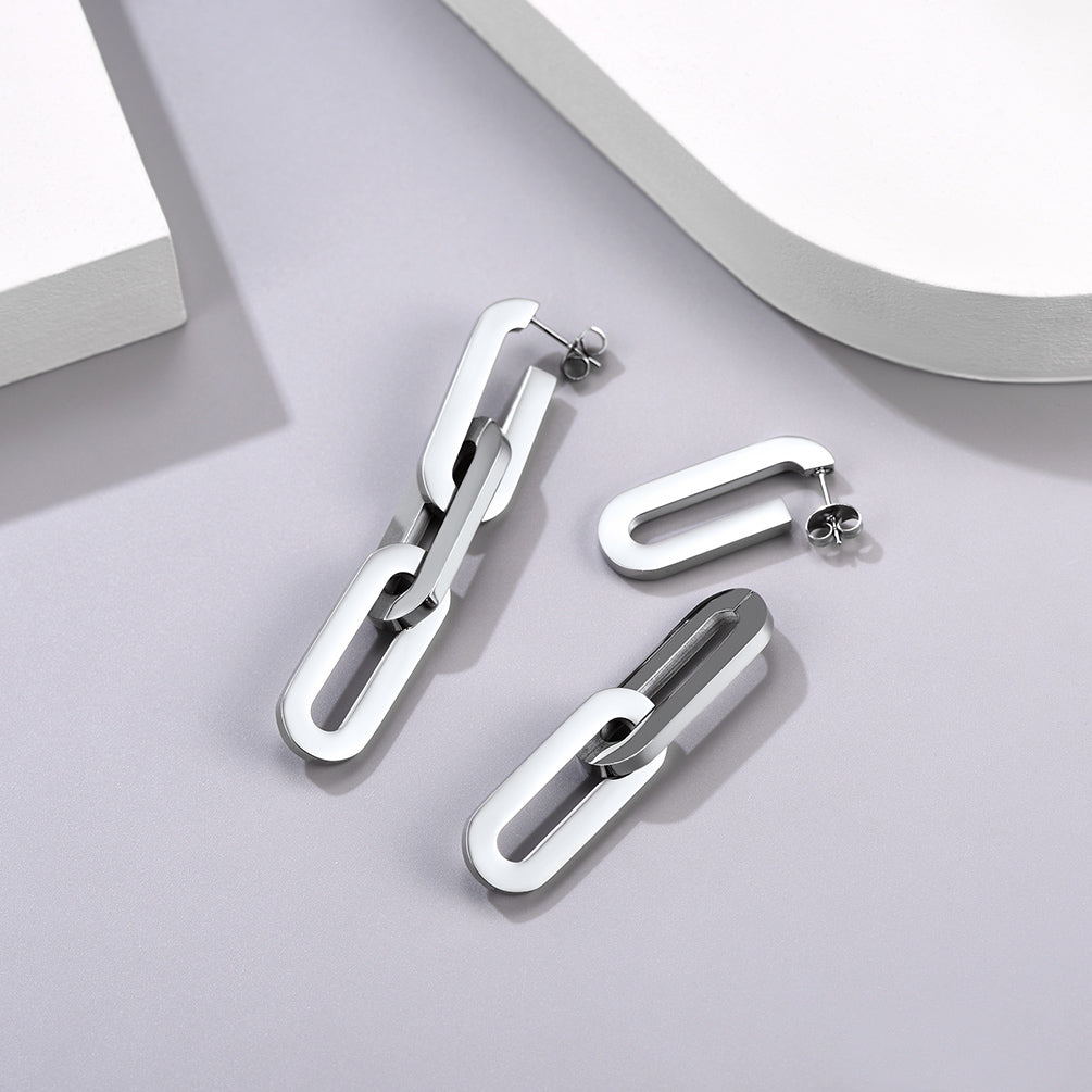 Pair of silver chain-style earrings on a light gray surface with a white background