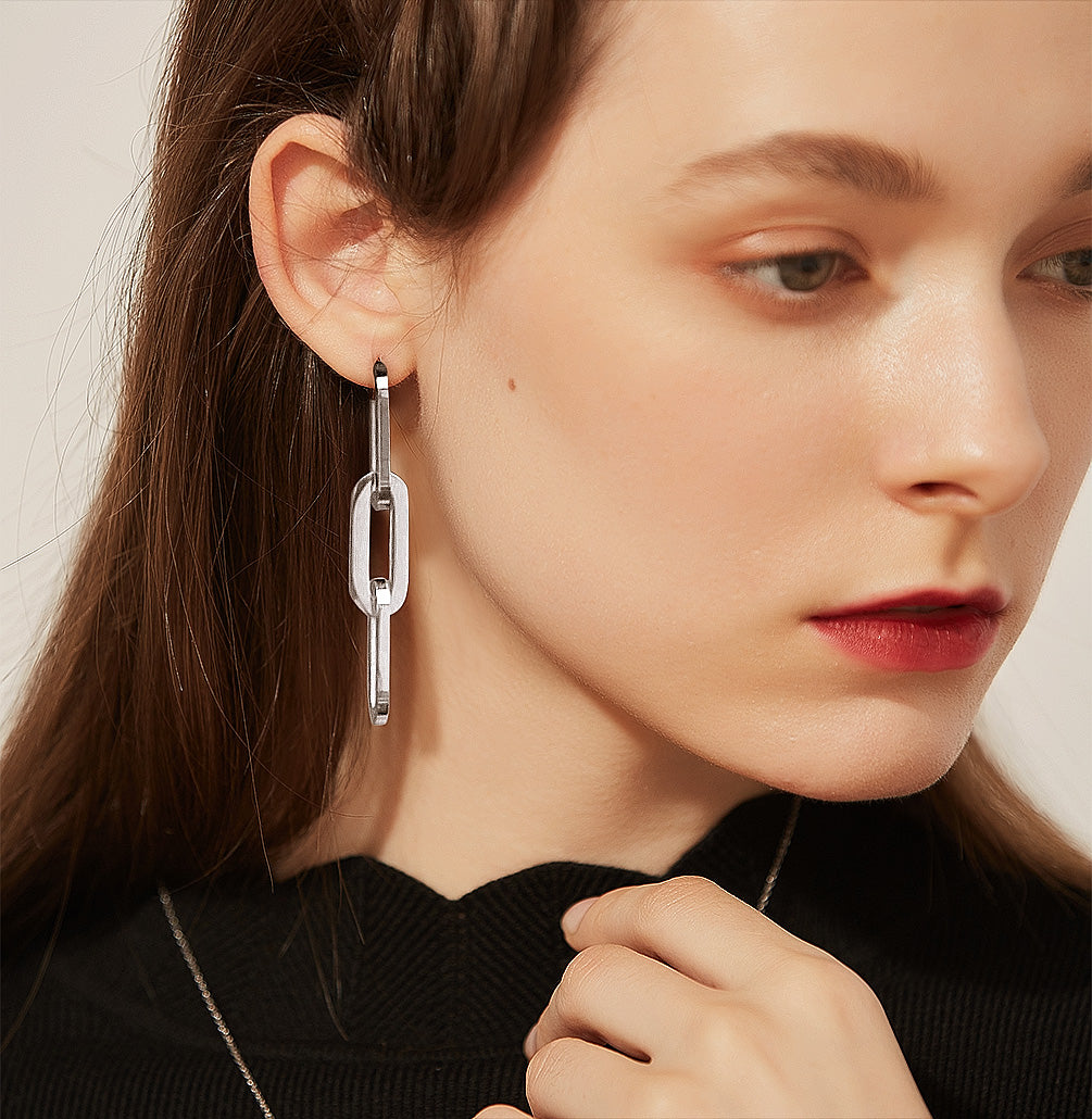 Close-up of a woman wearing a silver earring with a neutral background