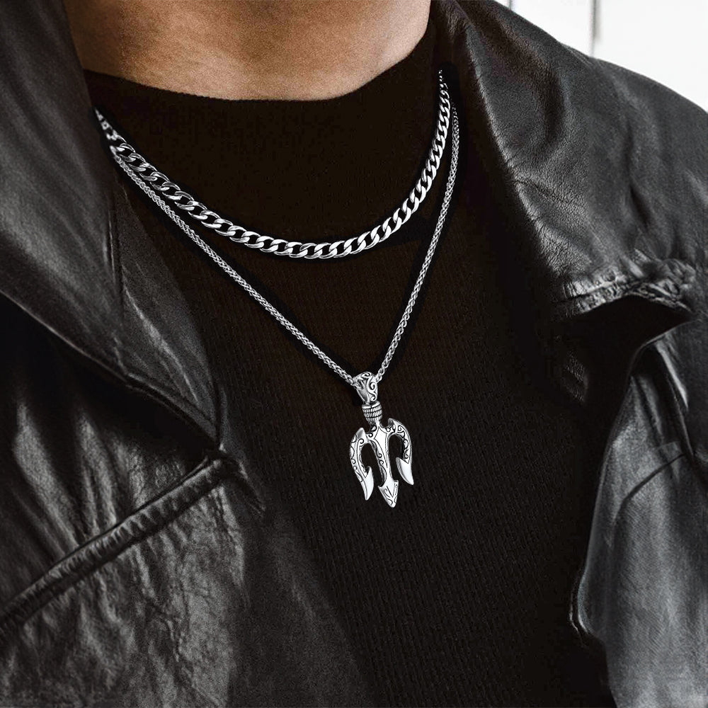 Person wearing a black jacket and black shirt with a silver chain necklace featuring a unique pendant.