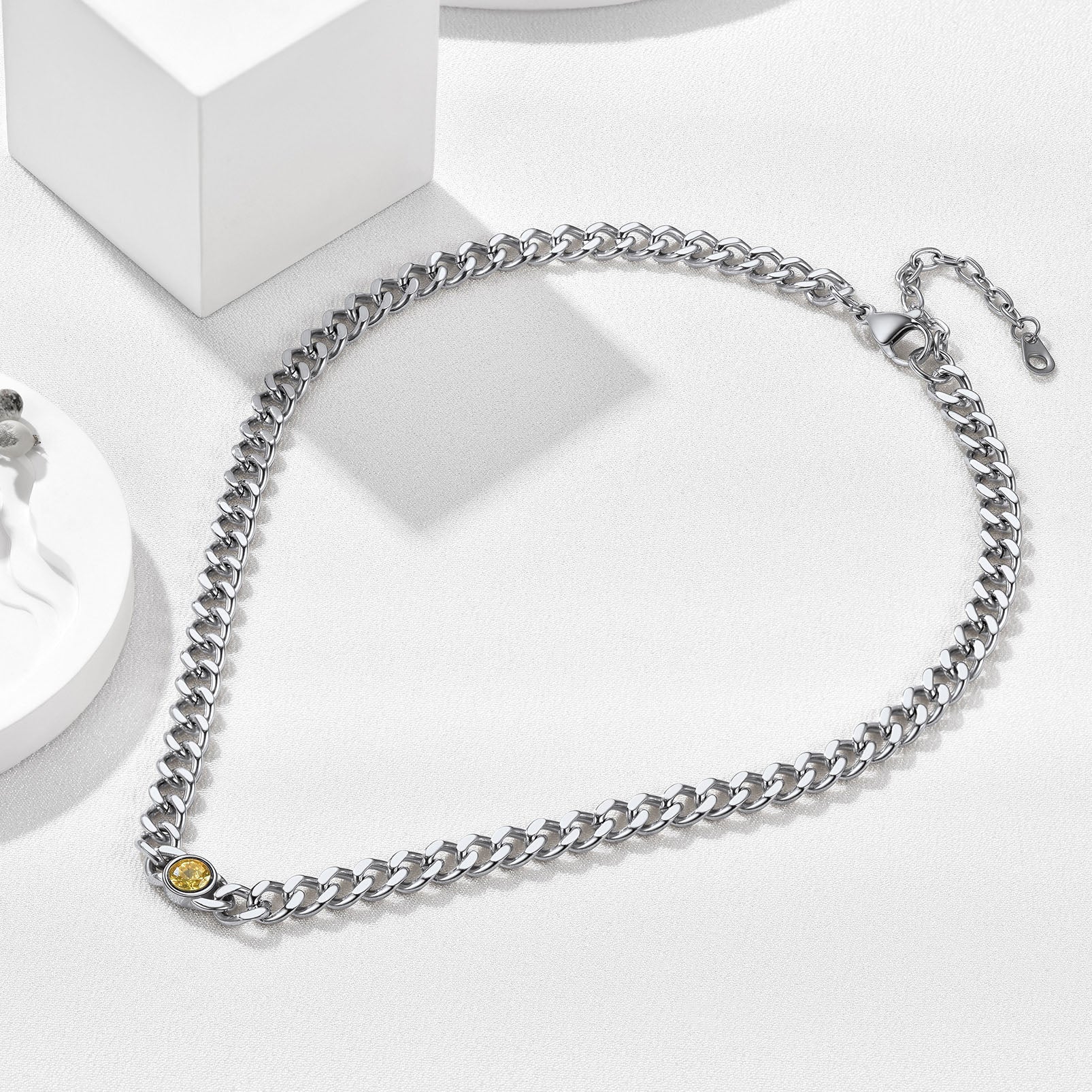 Close-up of Cuban chain necklace with red August birthstone