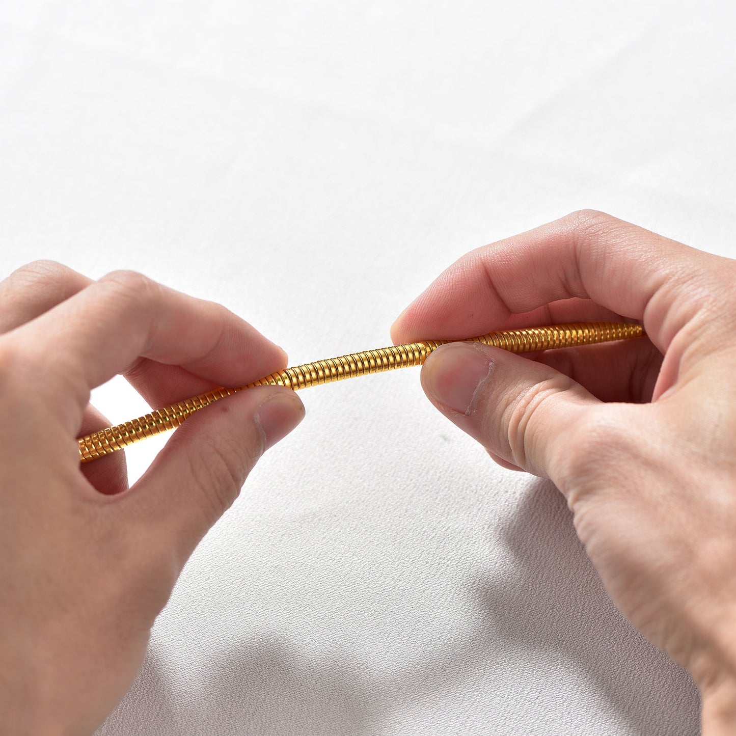 Close-up of flat snake chain texture and polished herringbone pattern in gold finish