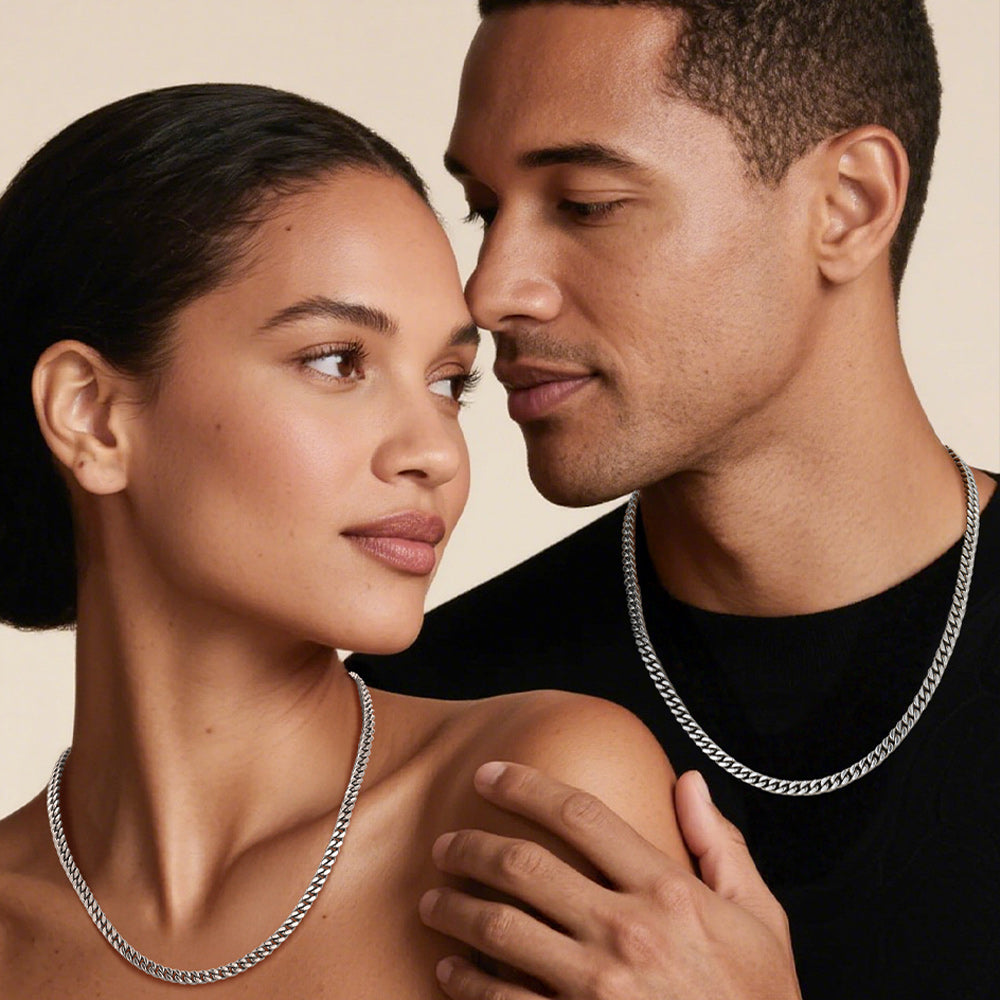 Man and woman wearing silver chain necklaces against a beige background