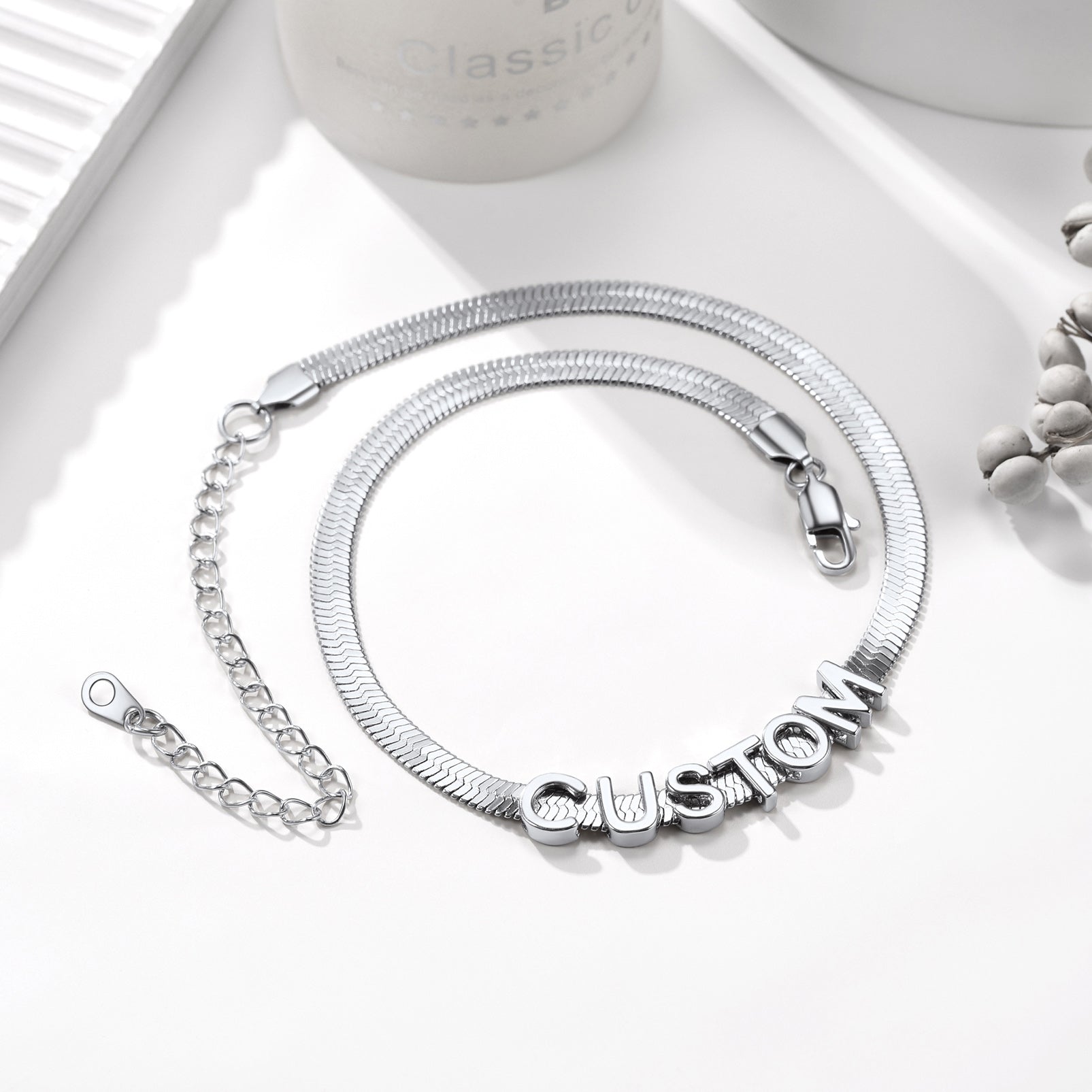 Silver bracelet with 'CUSTOM' charm on a white surface