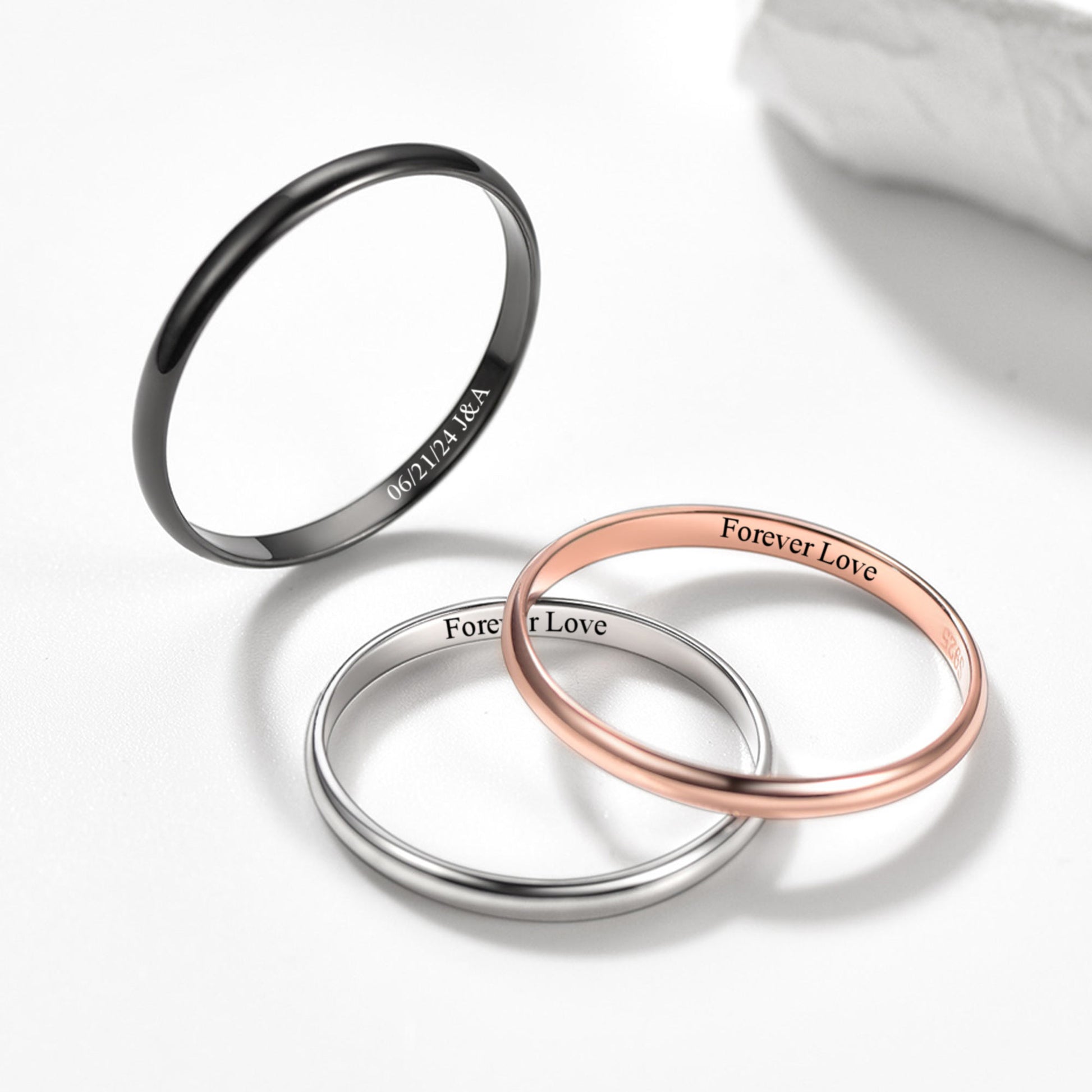 Three rings in black, silver, and rose gold on a white background with 'Forever Love' engraving.