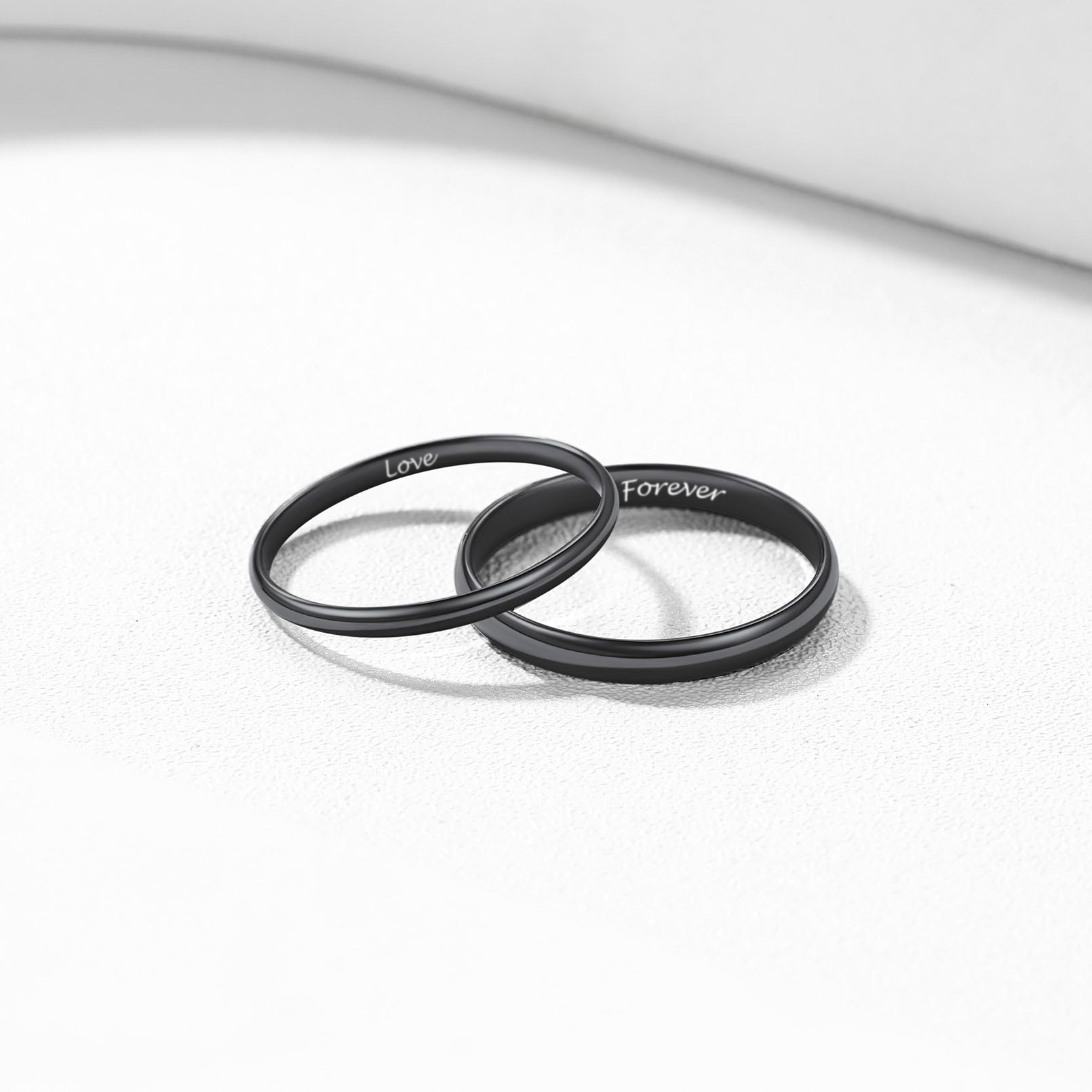 Two black rings with 'Love' and 'Forever' engraved on a white background