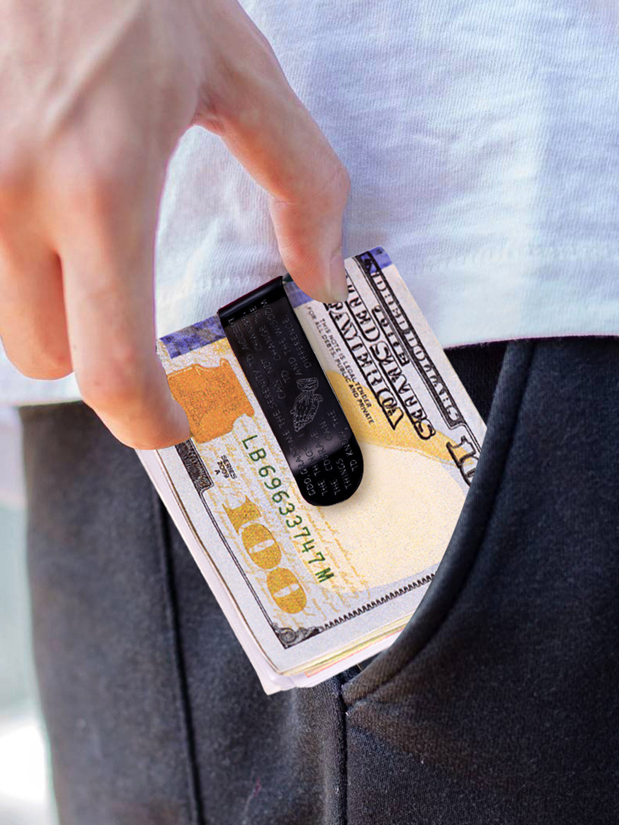 Man's hand putting a money clip with prayer on hundred dollar bills into his pocket