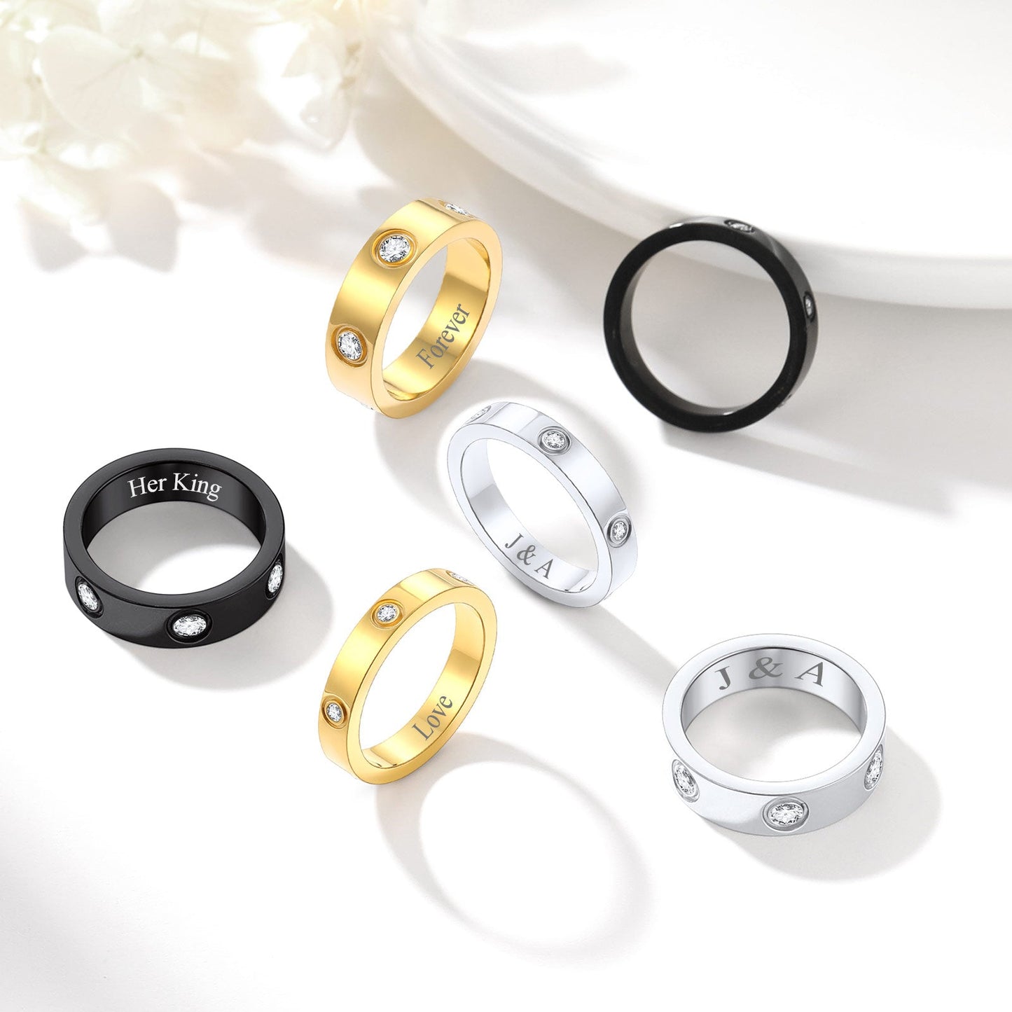 Set of gold, silver, and black rings with engraved text on a white background