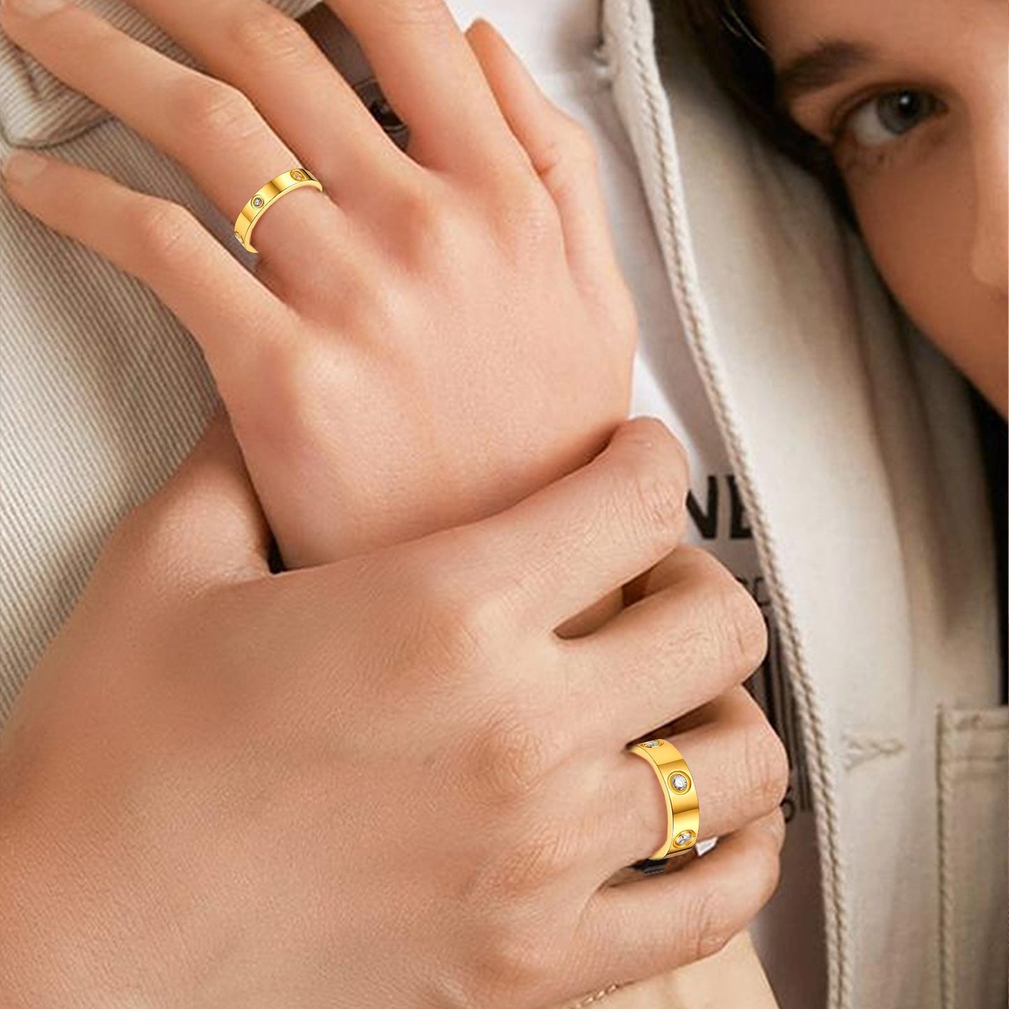 Close-up of two hands wearing gold rings with a neutral background