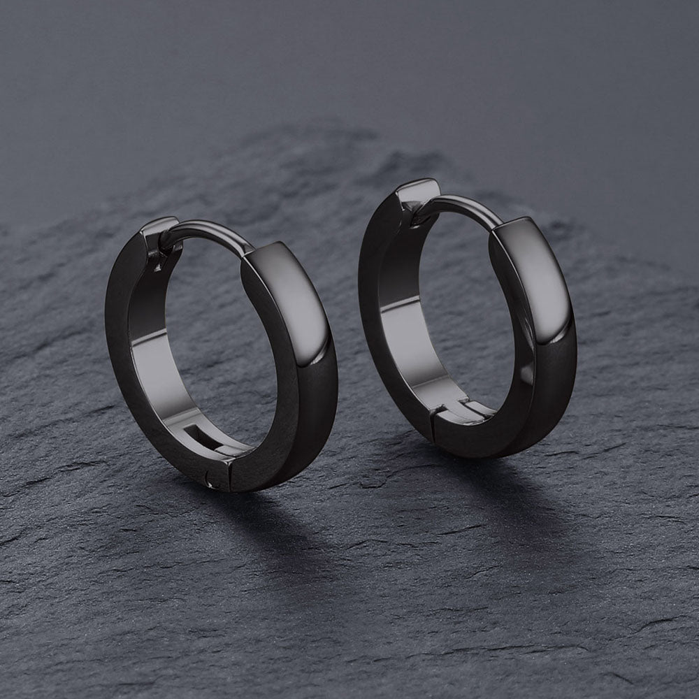 Black hoop earrings on a dark gray surface