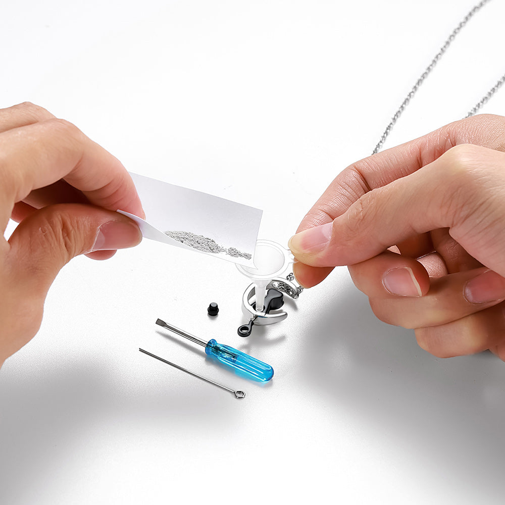 Person assembling a silver necklace with tools on a white background